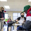 Students wearing masks work with a patient inside a classroom.