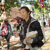 Student holding books standing on university campus path
